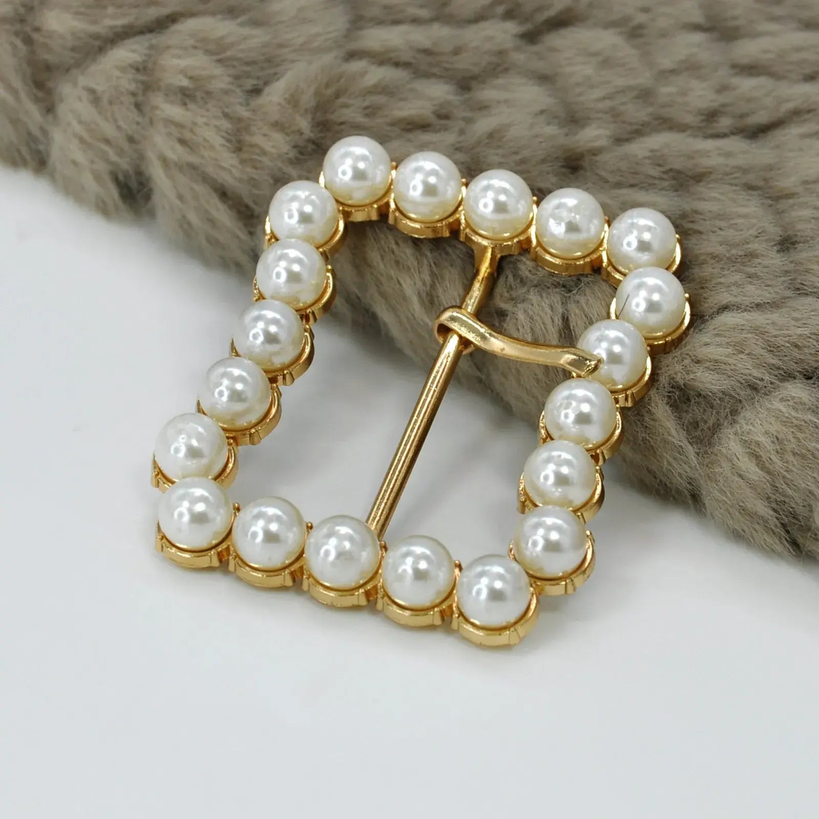 Pearl buckle. metal buckle, prong buckle shown in white background with fur
