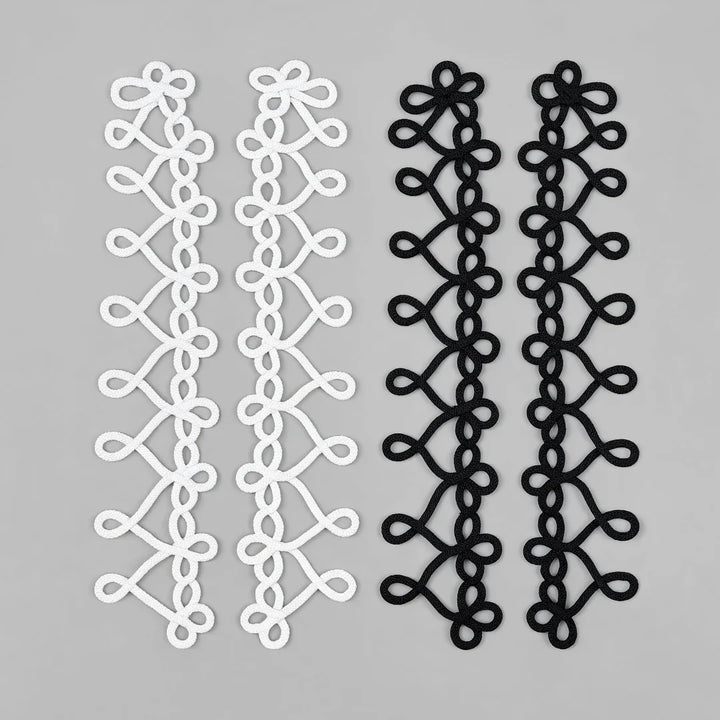 Interlocking heart loop braided cord sew-on patches in white and black, two pairs laid flat on grey background
