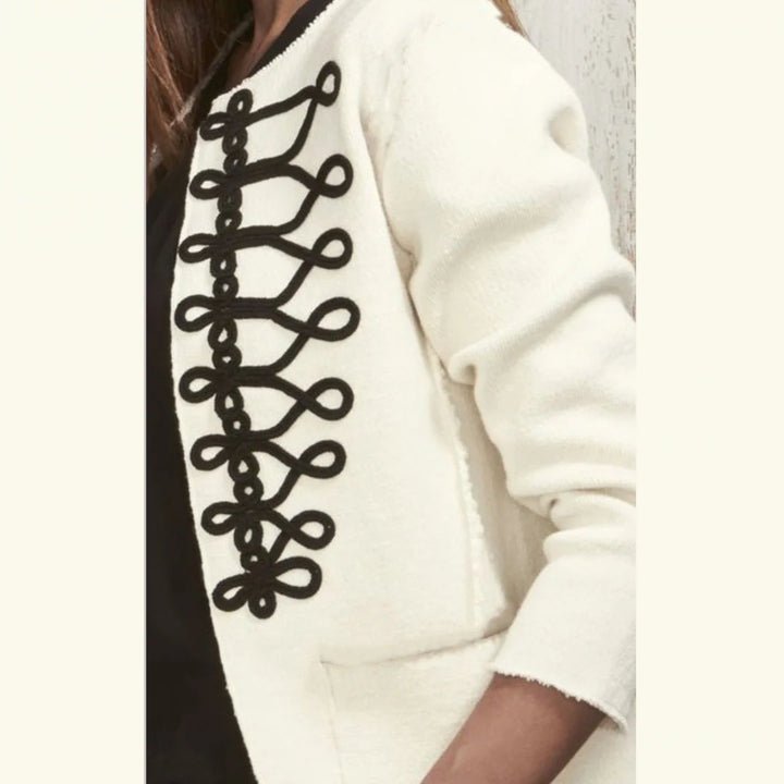 Close-up of a person wearing a cream-colored textured jacket with a prominent black decorative lace-up detail down the front.