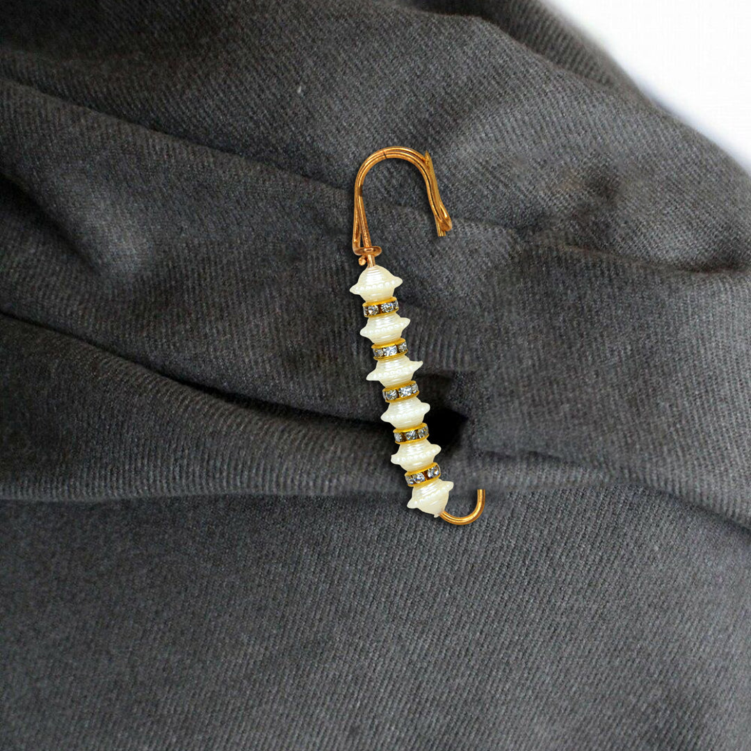 Decorative brooch with white stones and gold accents on a dark fabric background