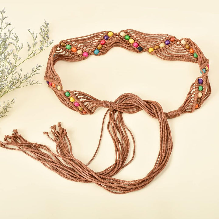 Ani Accessories Womens Belt Detailed overhead view of the central segment of a brown macrame belt, showcasing the staggered, vertical rows of colorful wooden beads (yellow, purple, green, pink, and natural wood tones) against a cream-colored surface.