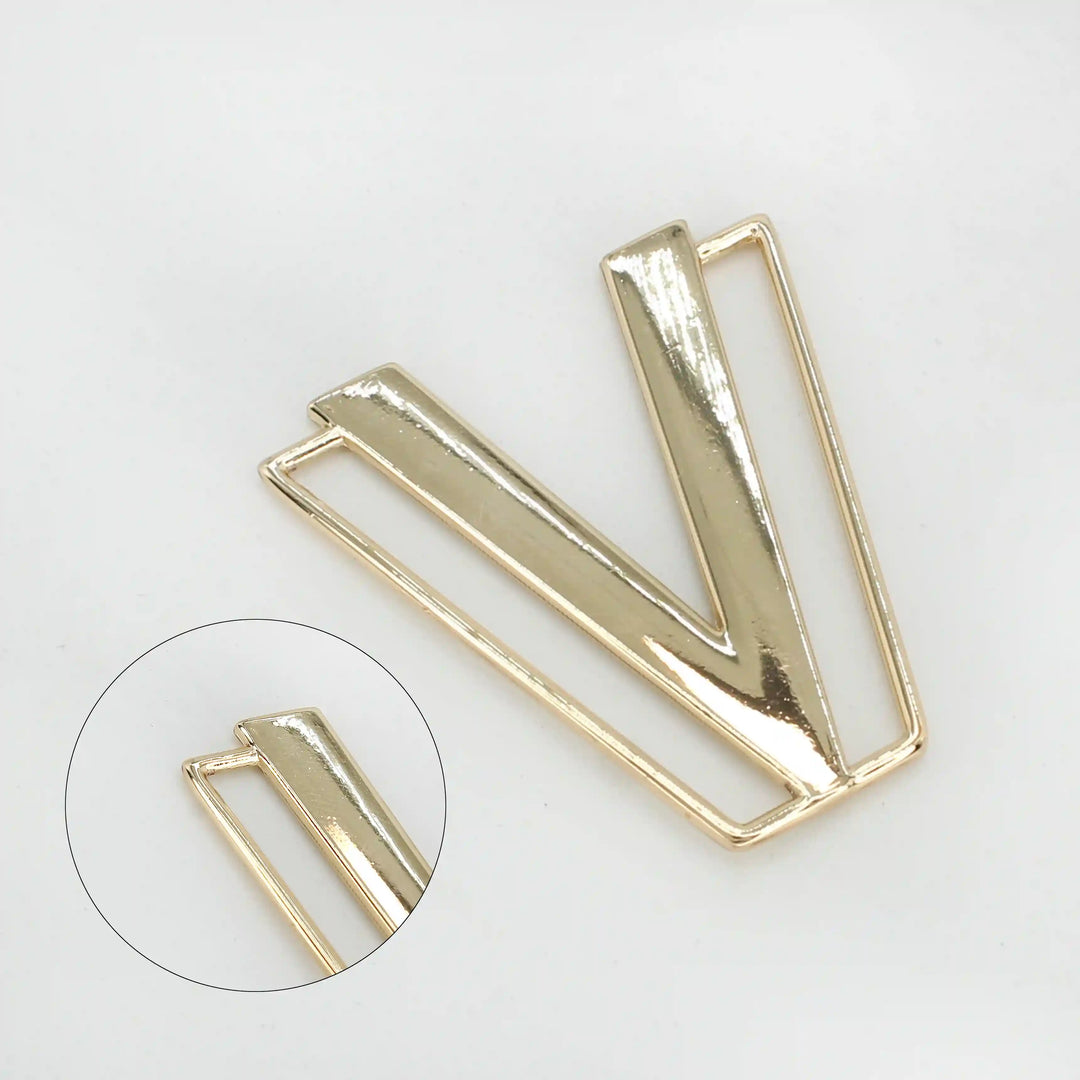 Ani Accessories  zooming image of shiny gold metal gematrical V buckle in a white background.