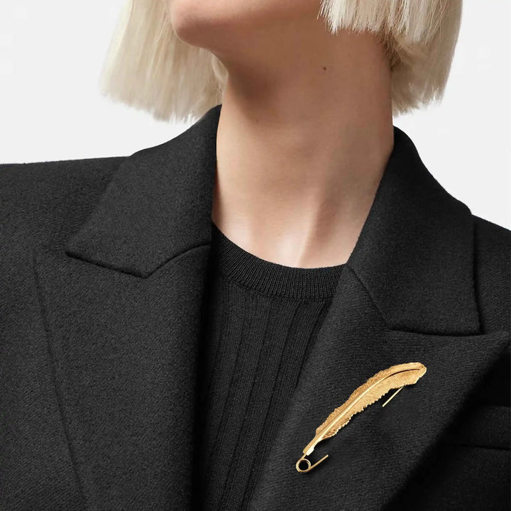 ani accessoires, model wearing black coat with a gold feather brooch on a plain background as a coat brooch & blazer brooch.