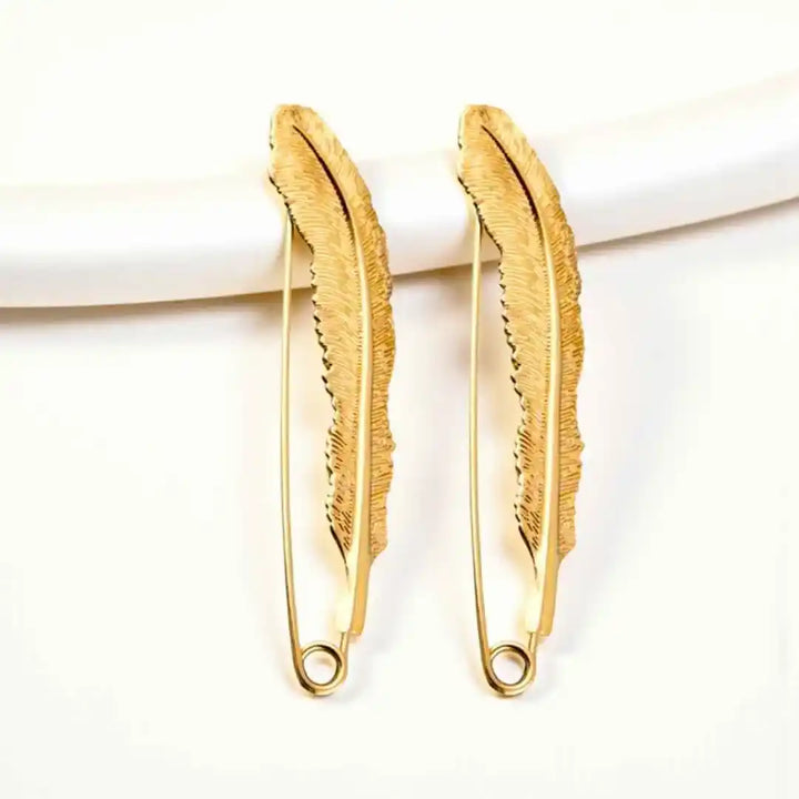 Gold feather-shaped safety pins on a white background. perfect to style as saree brooch, coat brooch, blazer brooch & more.