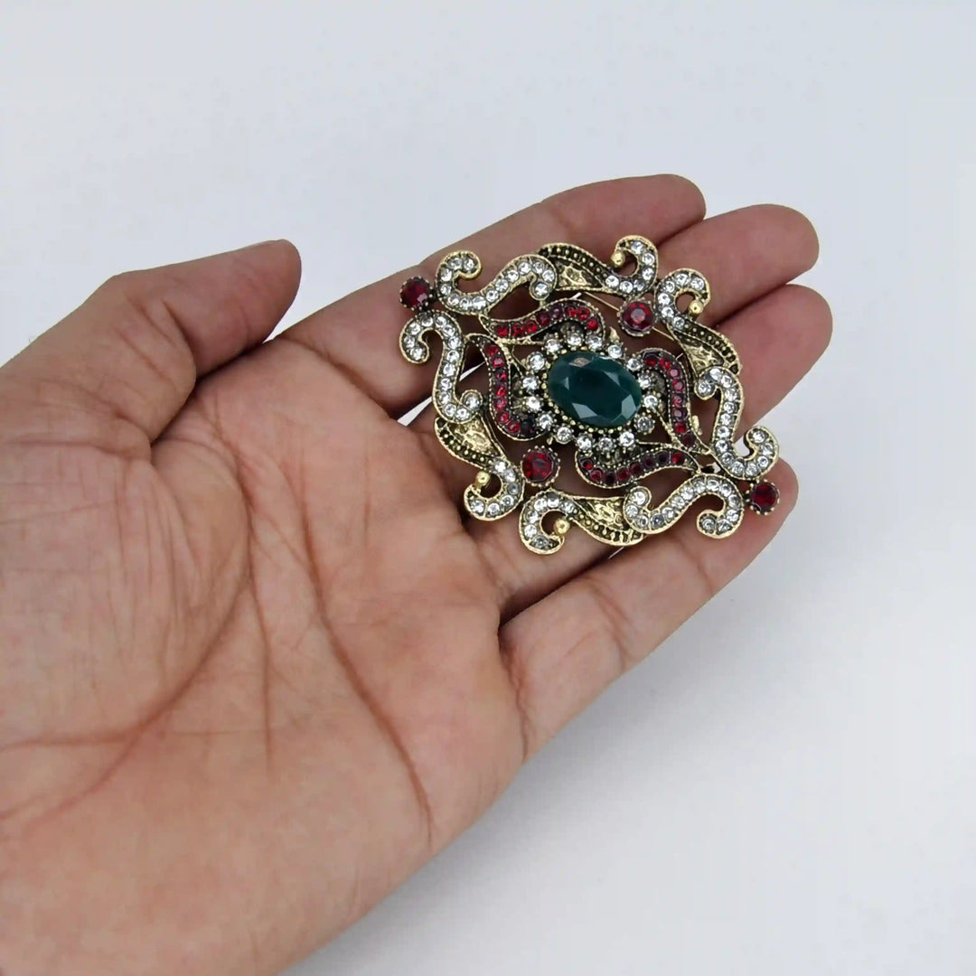 ANI Accessories antique gold green stone brooch held in hand to show its size 