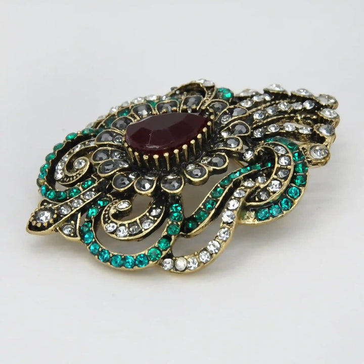 ANI Accessories antique gold Victorian brooch from a side angle showing the raised red stone and scrollwork with white color background 