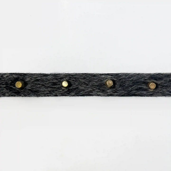 ANI Accessories black fur strip for clothes with gold metal studs laid flat with white color background 