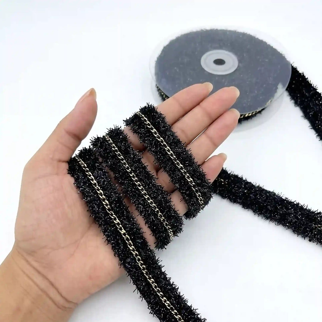 ANI Accessories black glitter lace with gold chain held in hand next to the roll with white color background 