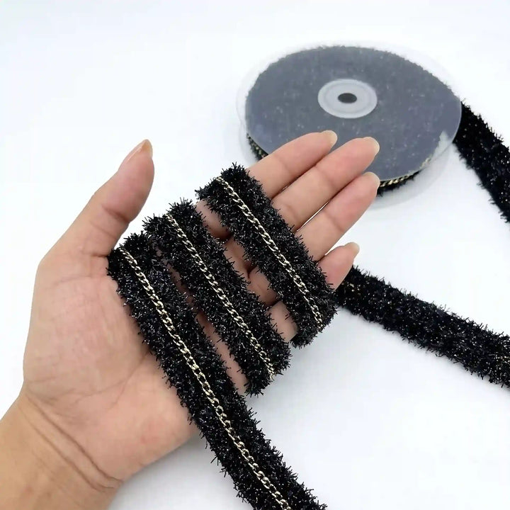 ANI Accessories black glitter lace with gold chain held in hand next to the roll with white color background 