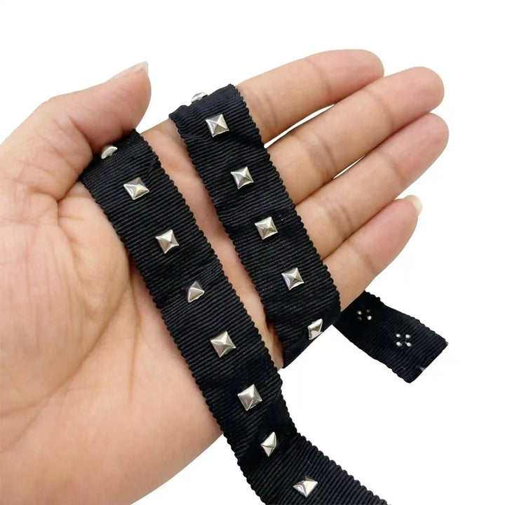 ANI Accessories black pyramid stud ribbon held in hand next to the roll with white color background 