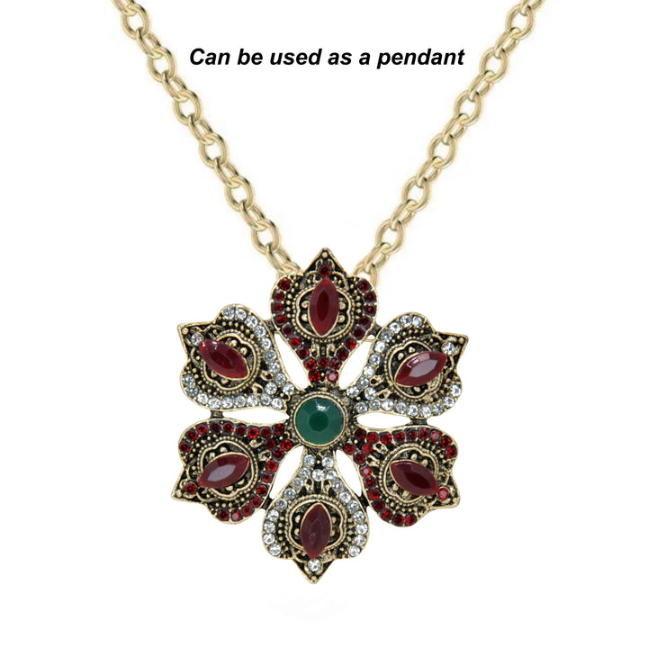 ANI Accessories antique gold flower brooch from an angle showing the raised red and green stones with white color background 