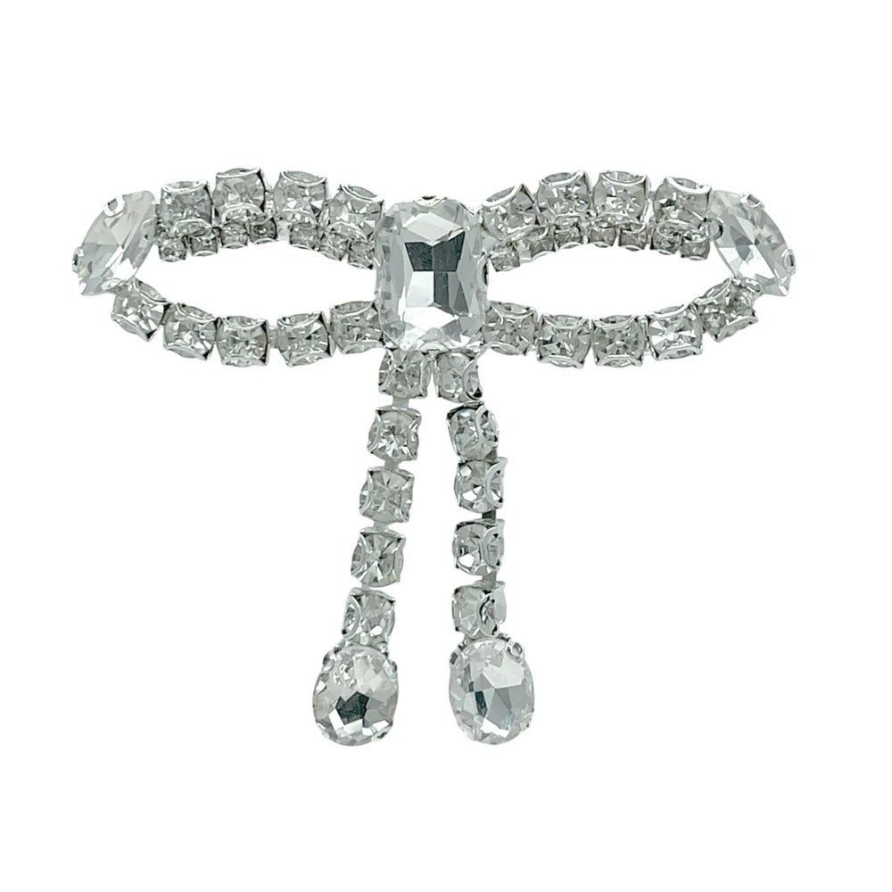 Silver crystal bow brooch with rhinestone chain loops, emerald-cut centre stone and two hanging oval crystal drops white color background 