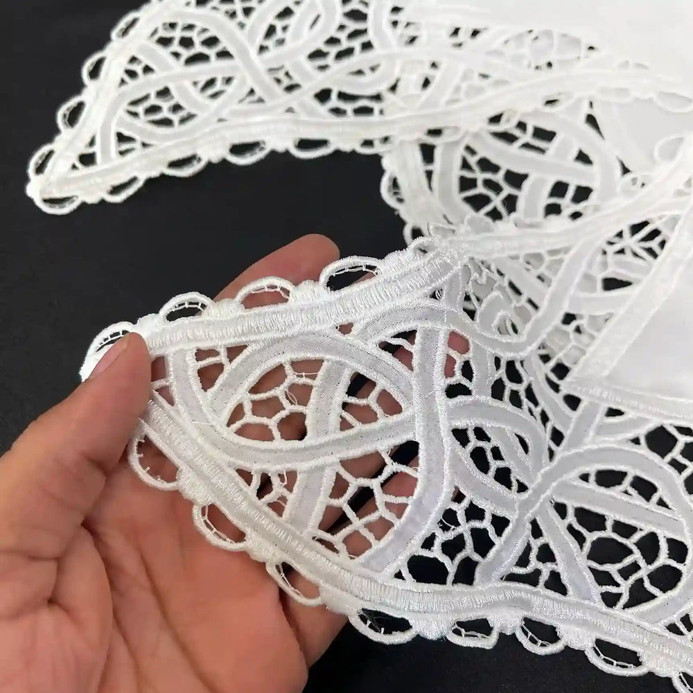 Close-up of the white cutwork lace collar with scalloped looped edge held in hand 