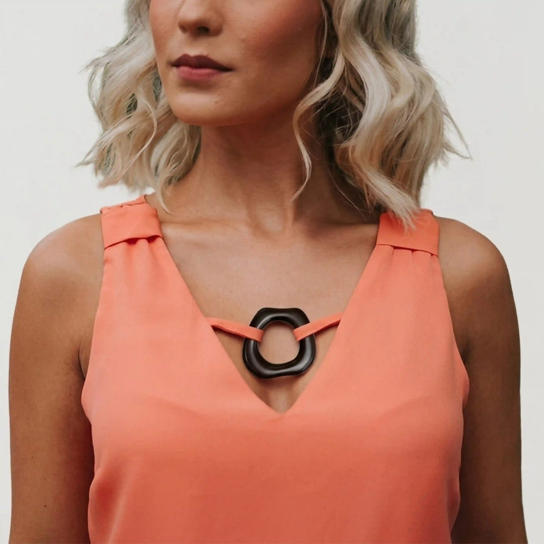 ANI Accessories dark brown organic ring charm used as a V-neck connector ring on a coral sleeveless blouse With white color background 