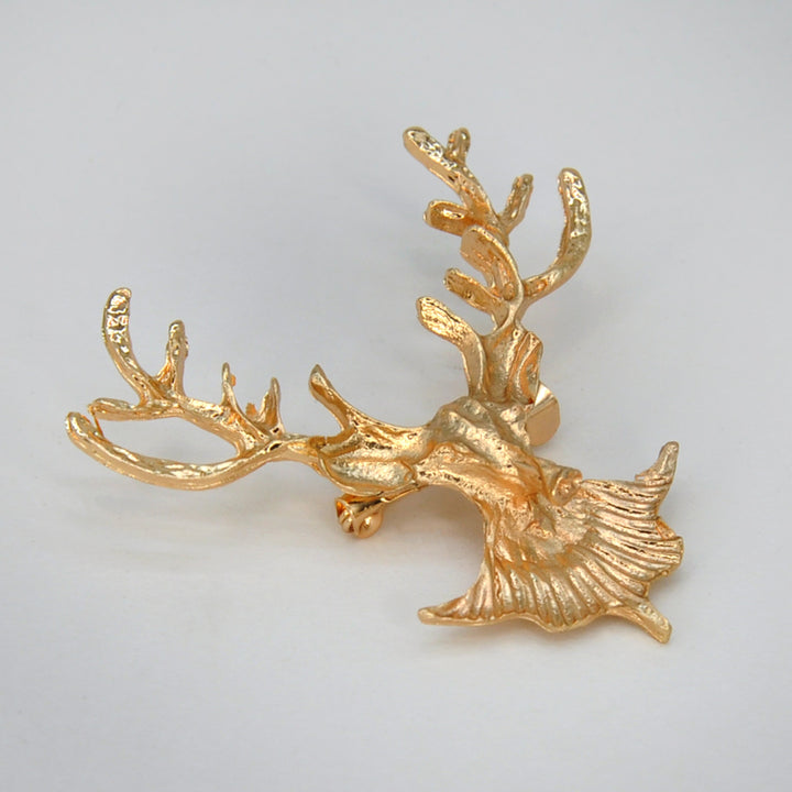 Side view of the gold deer head brooch showing the textured antlers with white color background 