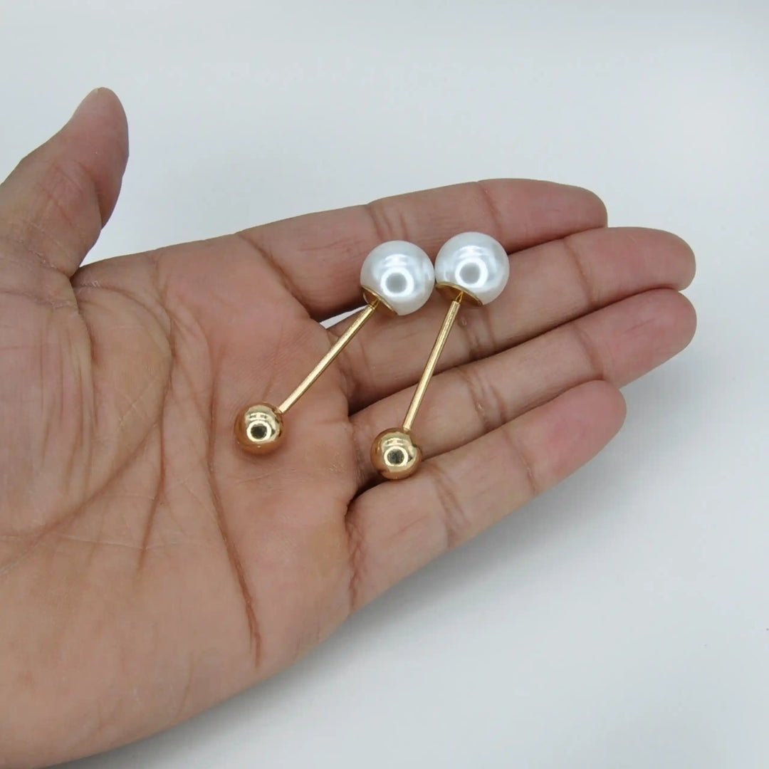 Two pearl and gold ball pins held in hand to show their small size with white color background 