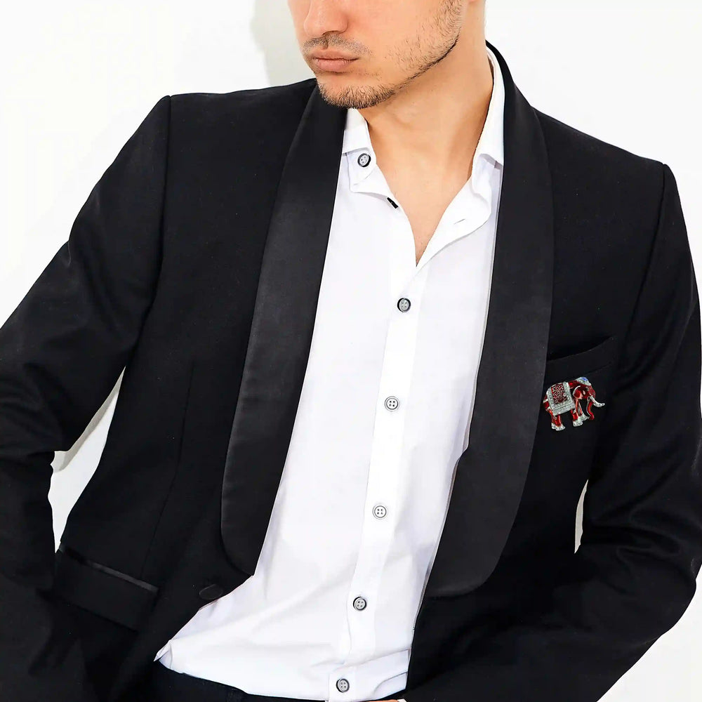 Man wearing an enamel elephant brooch on a black tuxedo jacket with white color wall background