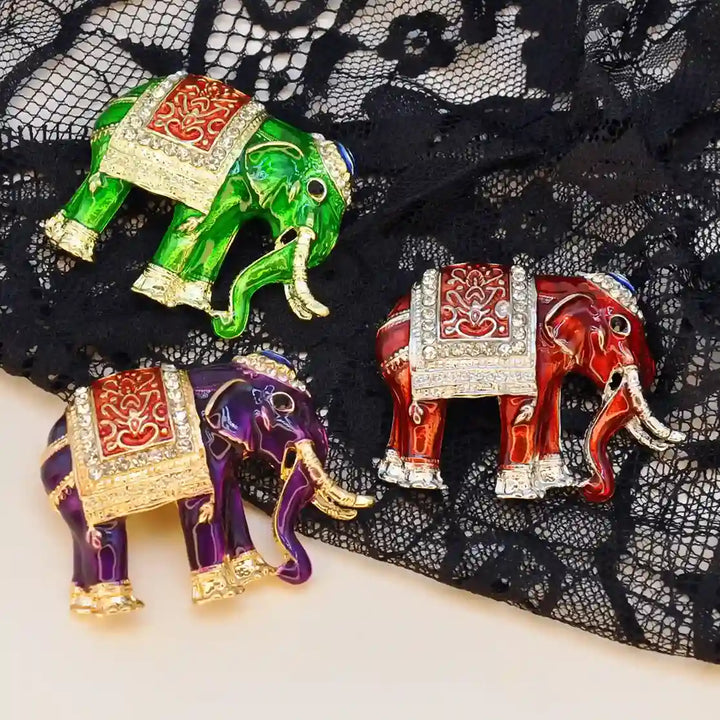 Red, purple and green enamel elephant brooches on black lace 
