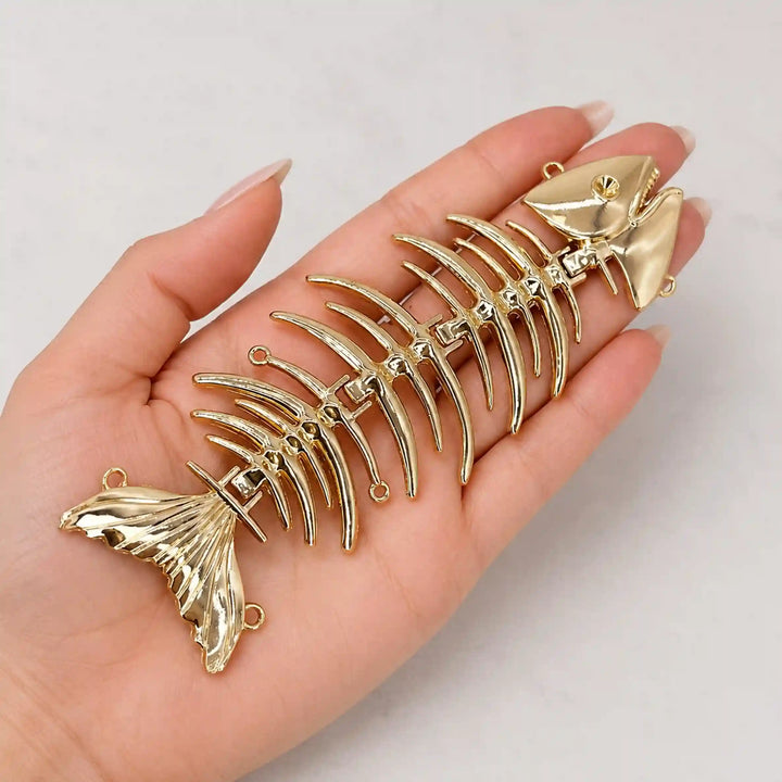 ANI Accessories gold fish skeleton embellishment held in hand to show its large size 