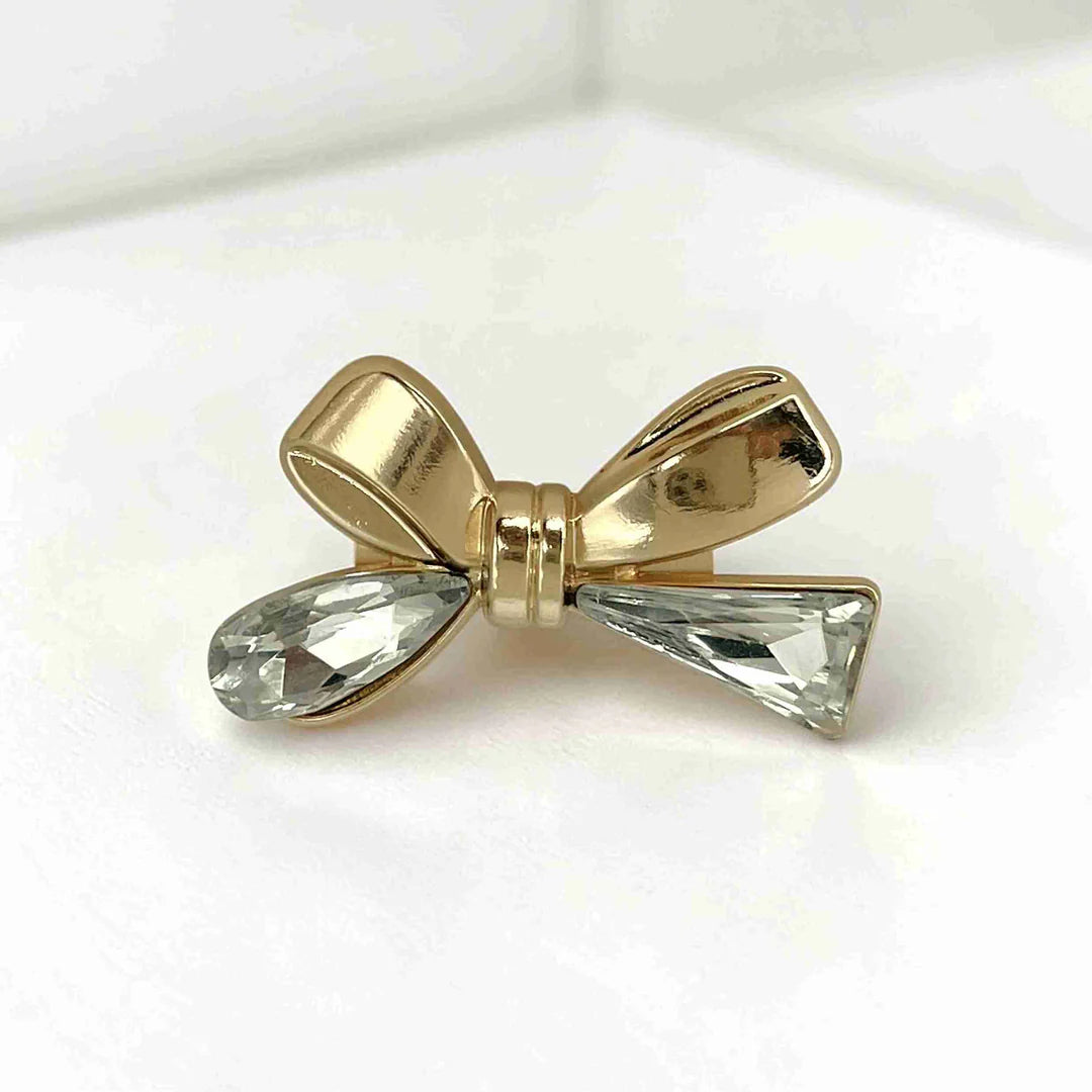 ANI Accessories gold bow brooch for women with teardrop and triangle crystal tails, on grey with white color background 