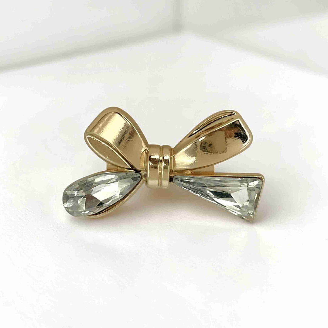ANI Accessories bow rhinestone brooch with gold loops and clear crystal tails, on white color background 