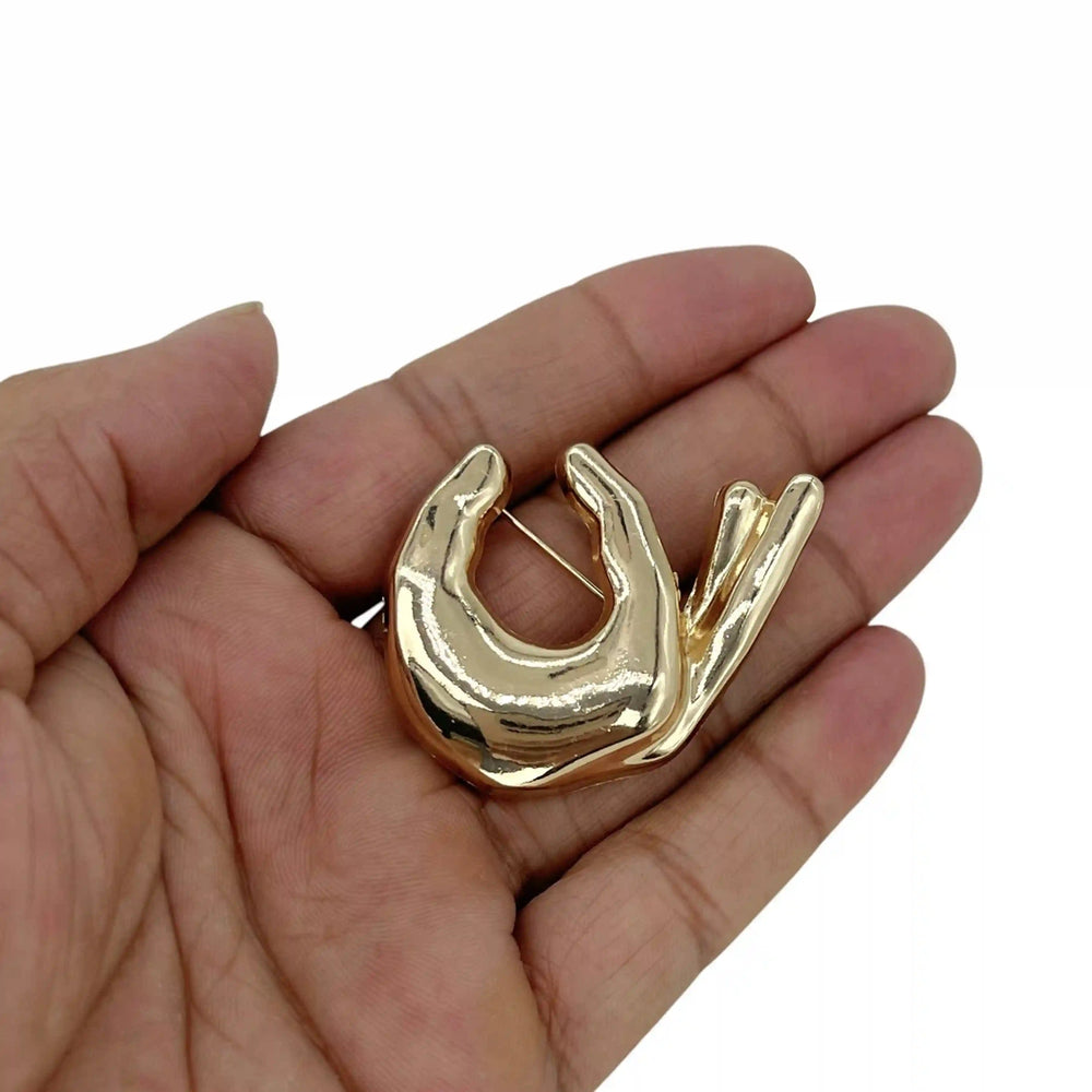 ANI Accessories gold hand brooch held in hand to show its size color background 