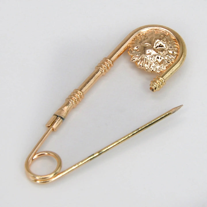 Gold lion head safety pin shown open with the lion medallion clasp with white color background 
