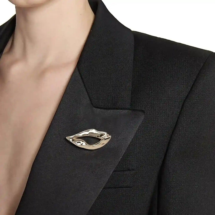 ANI Accessories gold lips brooch pinned on the lapel of a woman's black blazer 