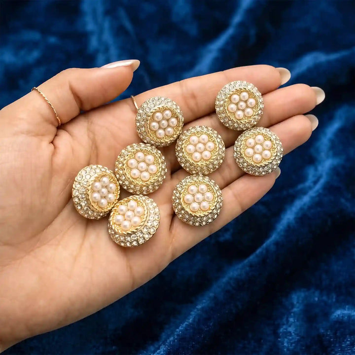 ANI Accessories gold pearl-look rhinestone cluster buttons in an open palm to show real size, on navy blue velvet color coth background 