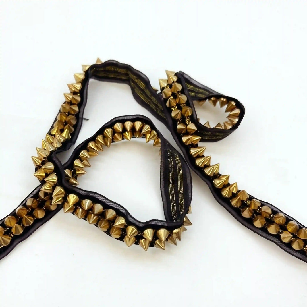 ANI Accessories gold stud trim on black tape, laid in a loose loop with white color background 