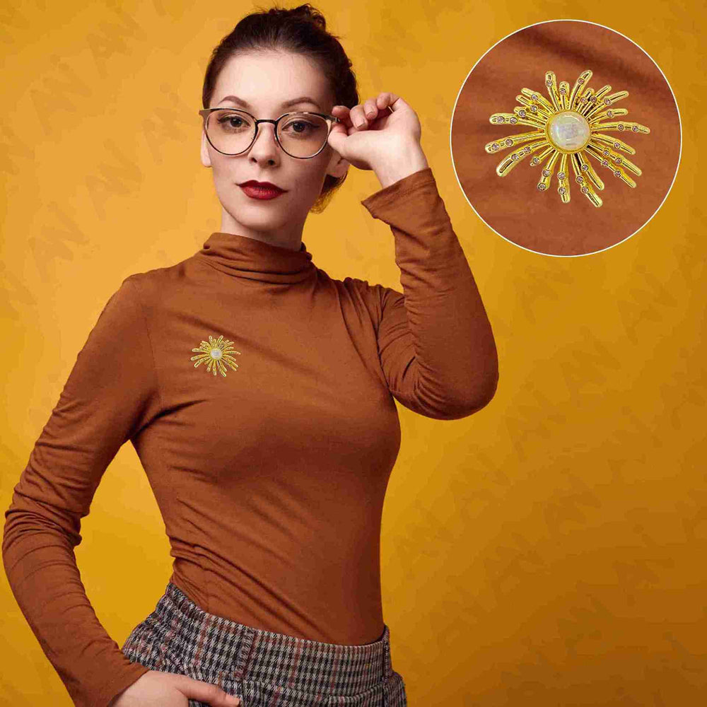ANI Accessories gold sunburst brooch worn on a woman's rust turtleneck sweater