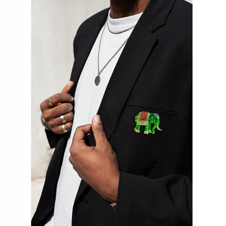 Man wearing a green elephant brooch on a black blazer for a party look