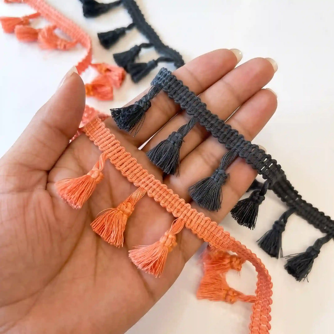 ANI Accessories latkan lace in orange and black held in hand to show the tassels with white color background 
