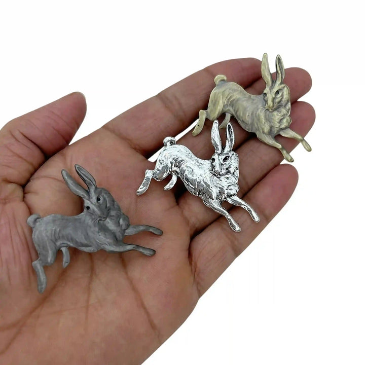 ANI Accessories leaping rabbit brooches in three colours held in hand to show their size 