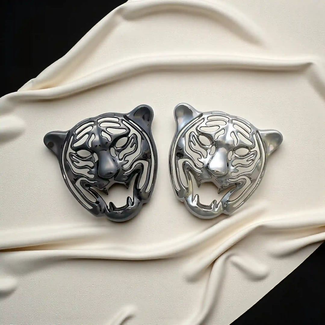 Silver and gunmetal metal tiger emblems on cream satin with white color background 