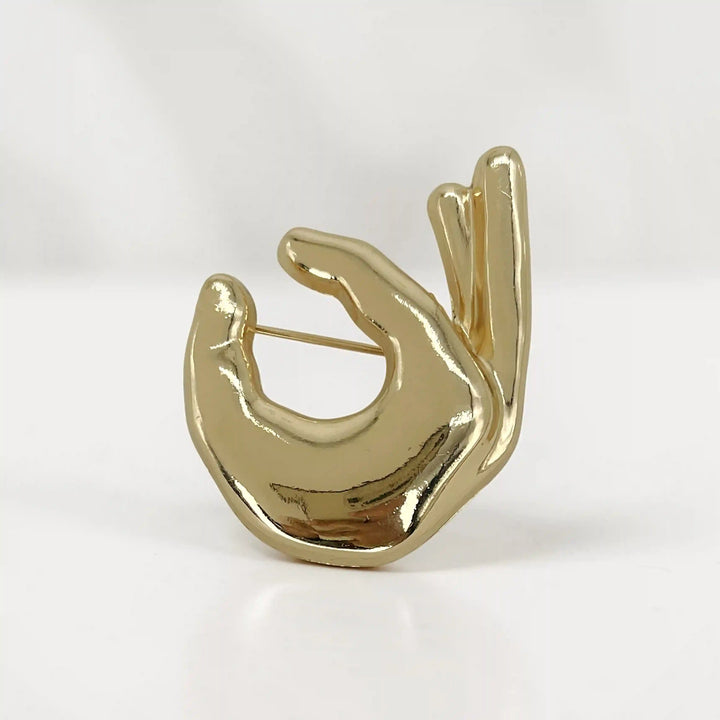 ANI Accessories OK hand gesture metal brooch in high-shine gold, on white color background 