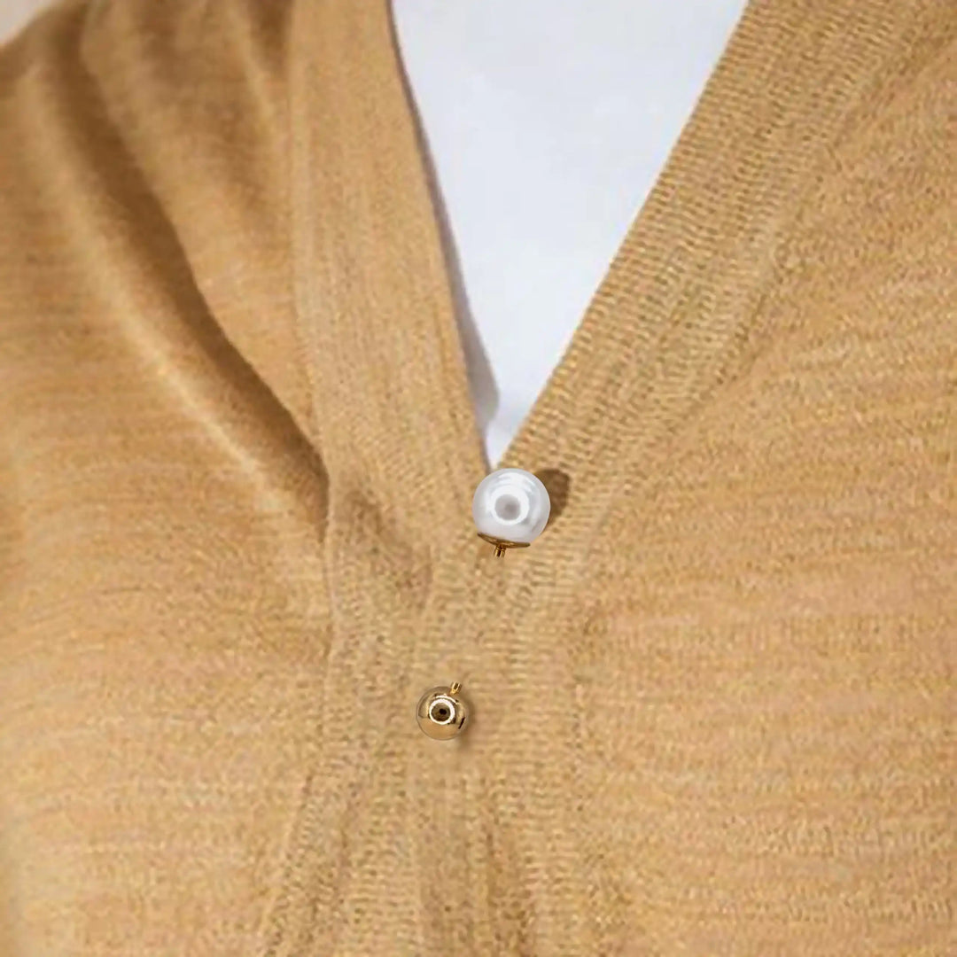 Pearl and gold ball pin used to close a mustard cardigan 