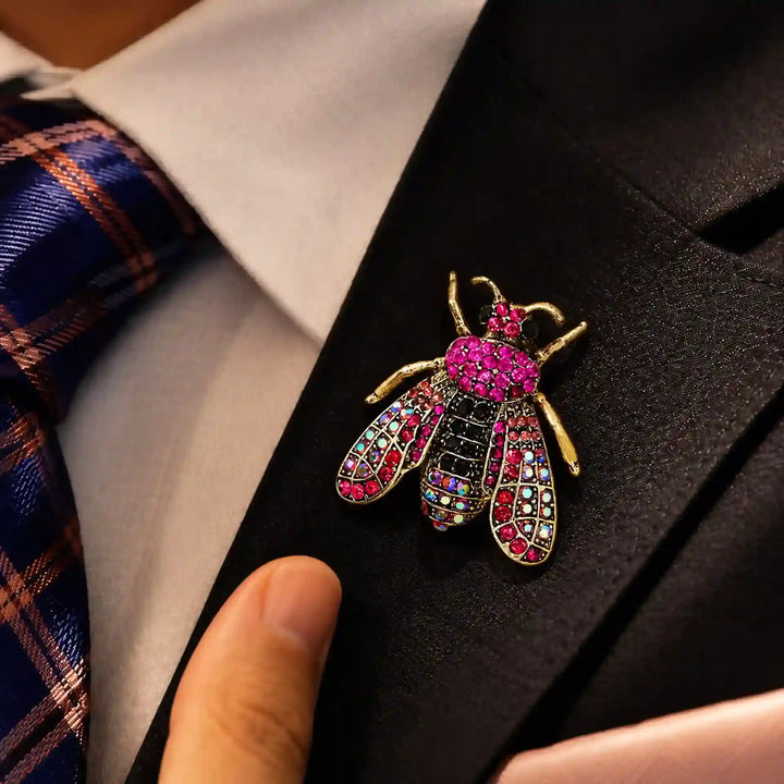 ANI Accessories pink honeybee crystal brooch on the lapel of a man's navy blazer 