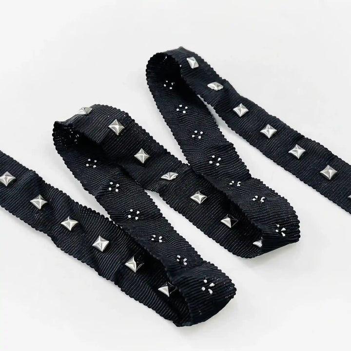ANI Accessories pyramid studs for clothing on black ribbon, folded in a zigzag with white color background 