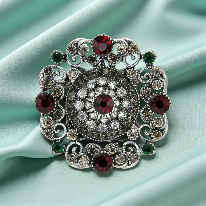ANI Accessories regal bloom vintage crystal brooch in antique silver with ruby-red and green stones on mint satin