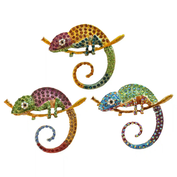Pink, green and blue rhinestone chameleon brooches on white coolor background 