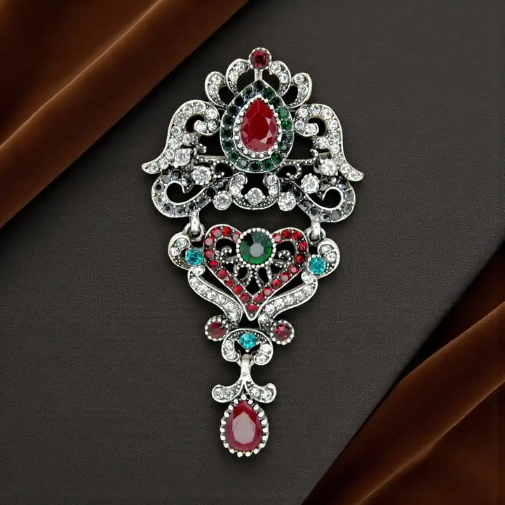 ANI Accessories royal heirloom crystal brooch in antique silver with ruby-red and green stones 