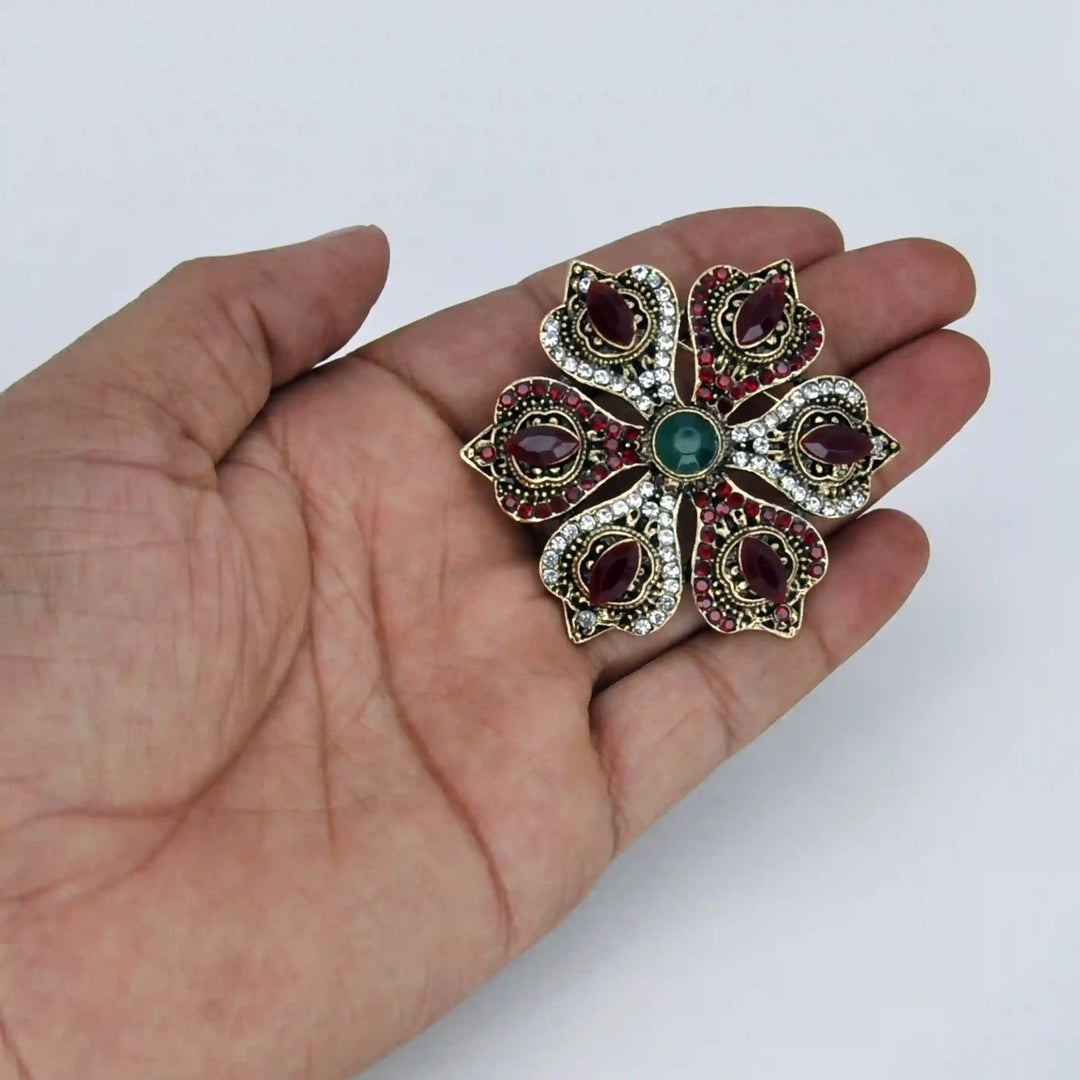 ANI Accessories ruby-red corsage brooch held in hand to show its size with white color background 