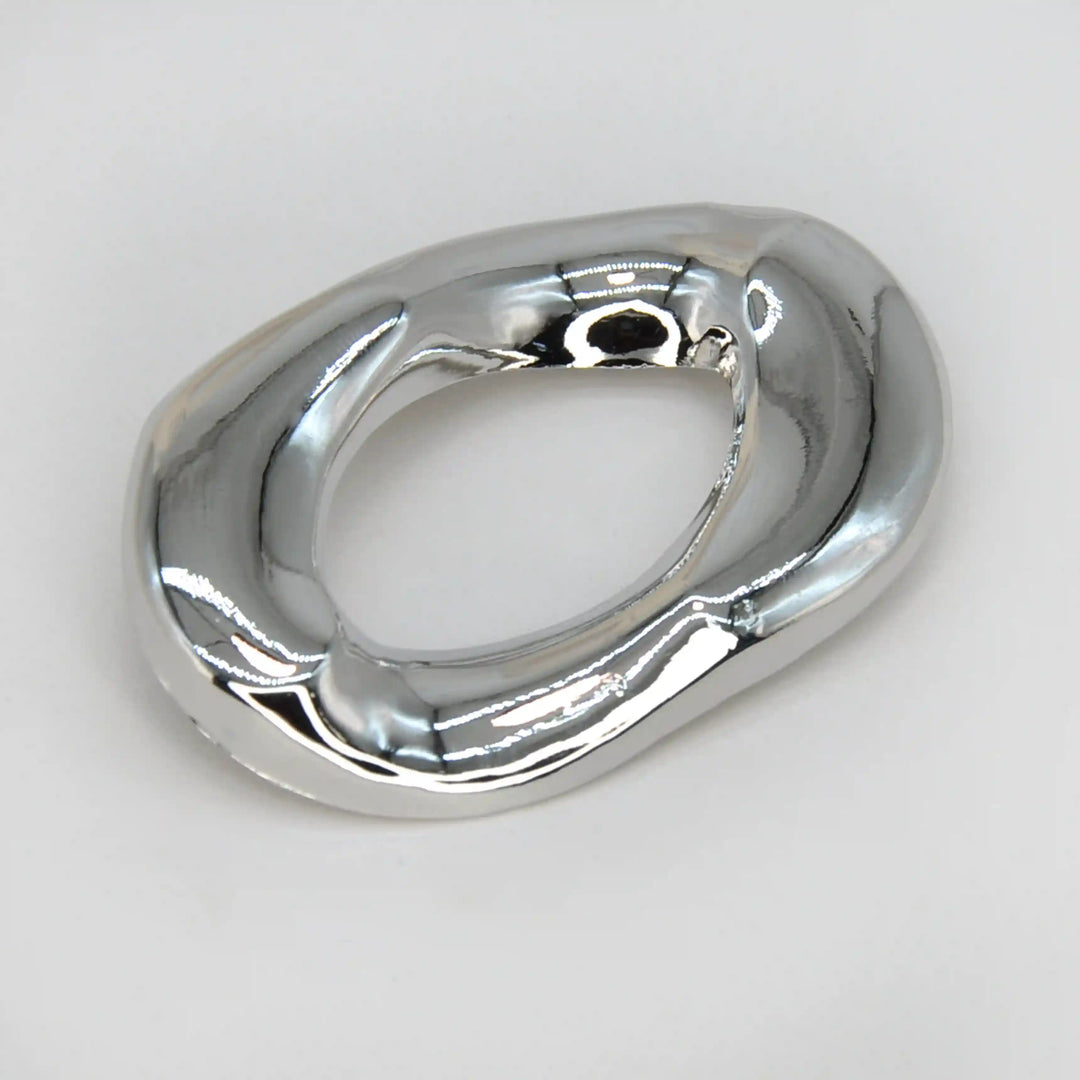 ANI Accessories silver abstract brooch, open oval ring with a molten chrome finish, on grey