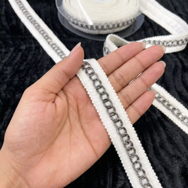 ANI Accessories silver lace for white suit held in hand next to the roll with white color background 