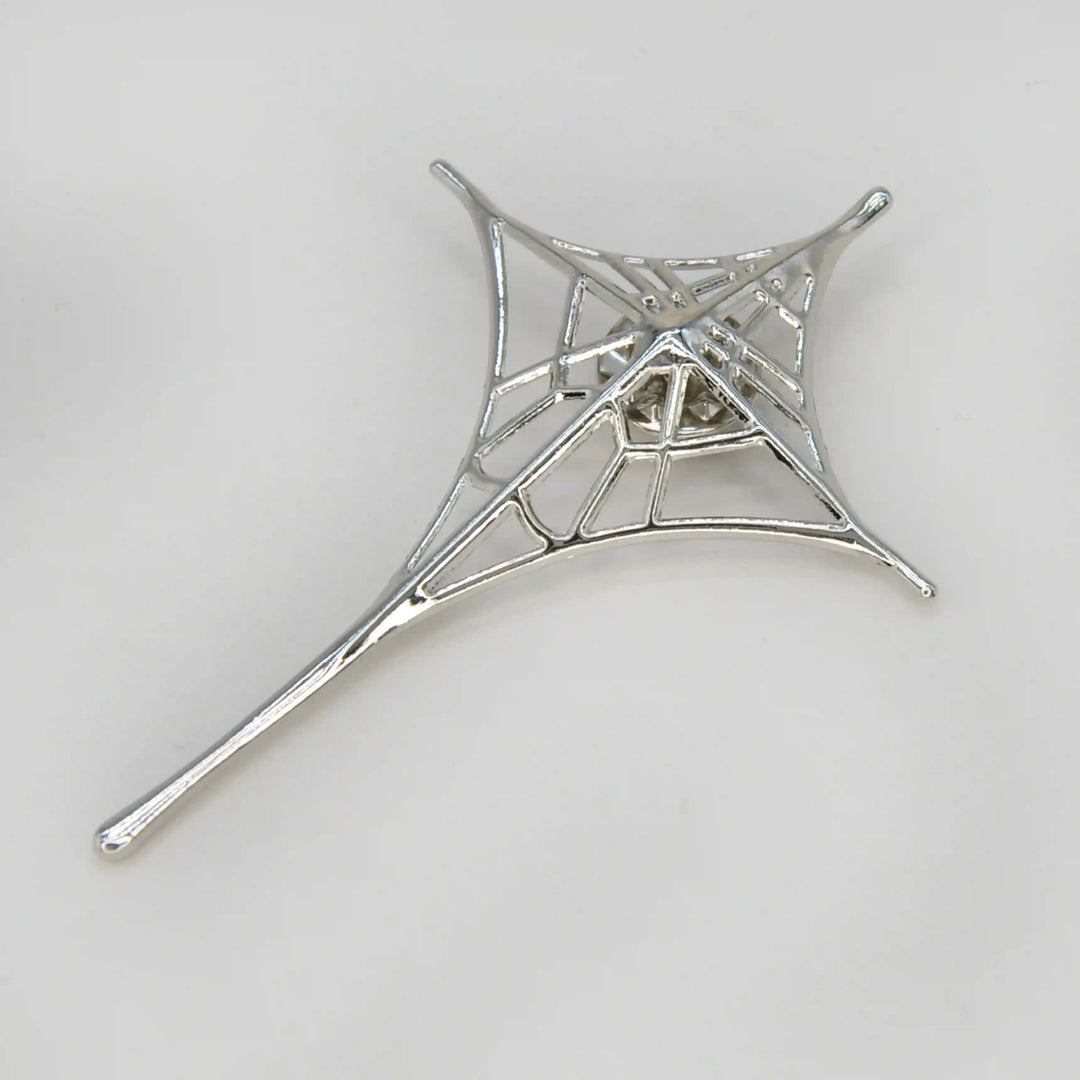 ANI Accessories silver spider web brooch in a four-point star shape with a long tail, on grey 