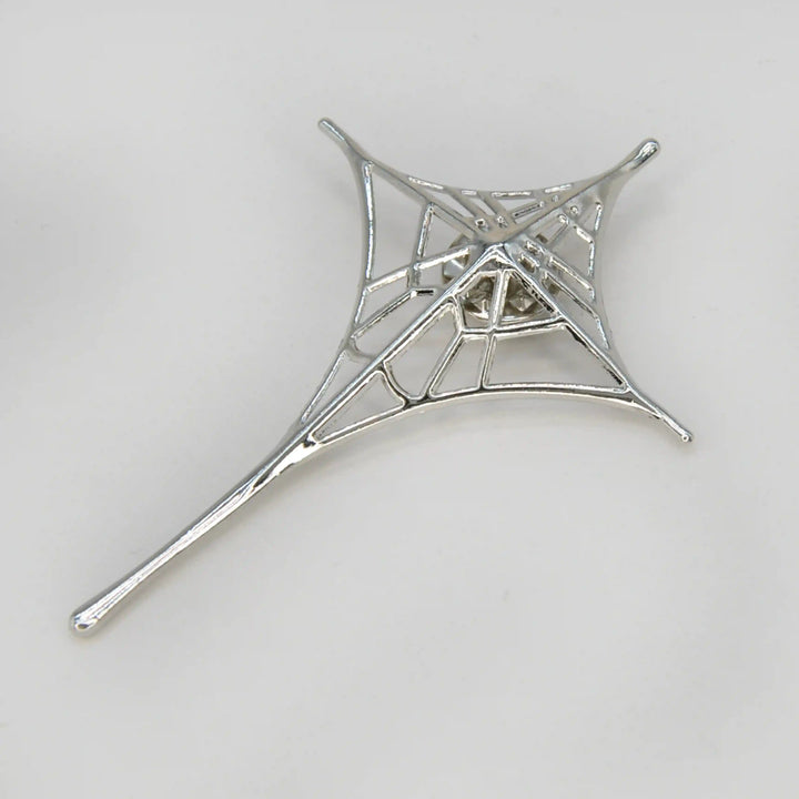 ANI Accessories silver spider web brooch in a four-point star shape with a long tail, on grey 