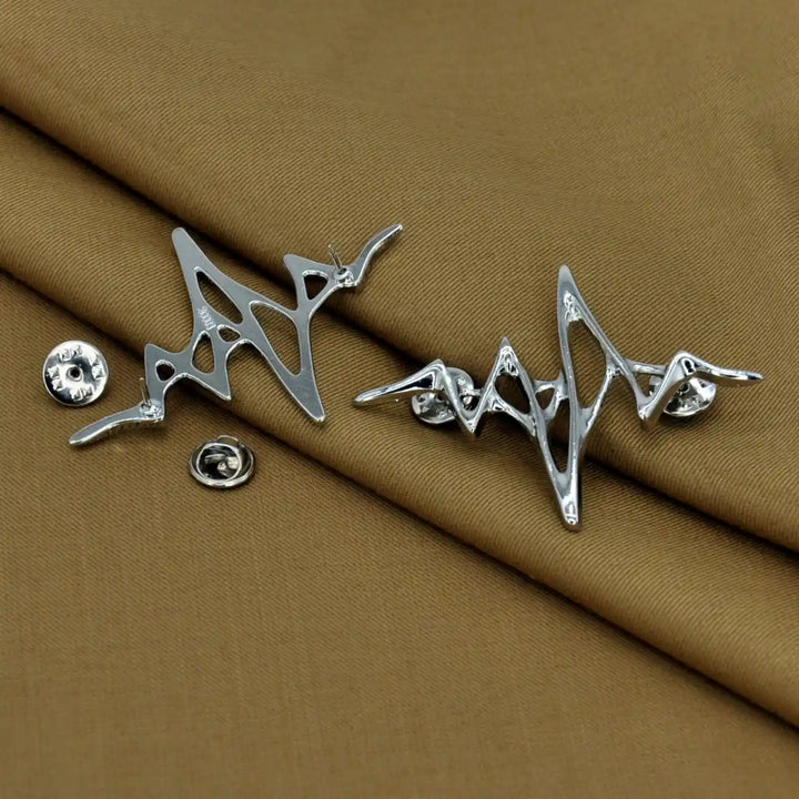 ANI Accessories two silver wave brooches with butterfly clutches removed, on tan fabric 