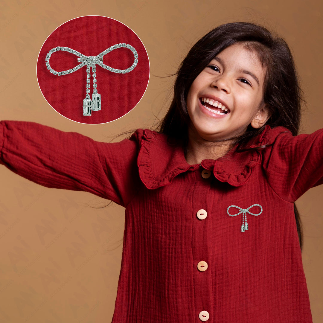 Sparkling Bow Brooch with Hanging Sapphire Two Stone attached to a red shirt, worn by a smiling girl