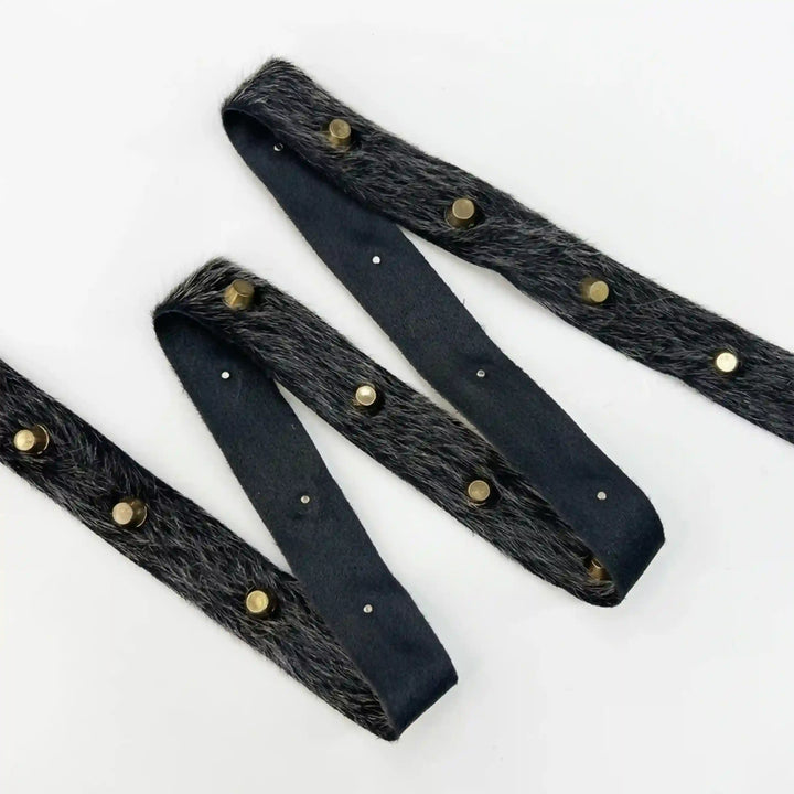 ANI Accessories studded fur trim metal eyelet lace in black with gold studs, folded in a zigzag with white color background 